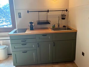 A kitchen with a wooden countertop, a sink, and a window with a view of snow-capped mountains.