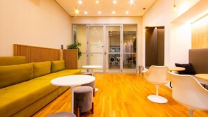 Un interior moderno con un sofá amarillo, mesas redondas y un panel de pared de madera.