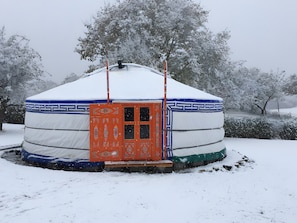 A yurt with a patterned door and a snow-covered landscape.