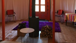 Een joert met een centrale kachel, twee stoelen, een tafel en een paars tapijt.