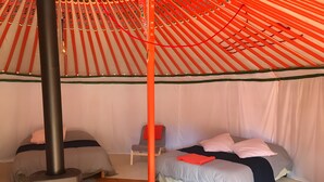 Een kamer met twee bedden, een stoel, een verwarming en een tentachtige constructie.