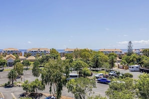 Zona residencial amb diversos edificis d'apartaments, un aparcament i una vista despejada de l'oceà.