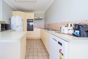 A compact kitchen with a microwave, refrigerator, oven, and dishwasher. - 3BR Apt + Pool Great Location Opp Beach & Park (Urangan)
