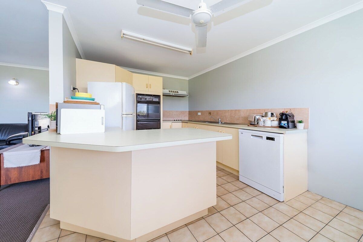 A compact kitchen with a central island, a built-in oven, and a dishwasher.