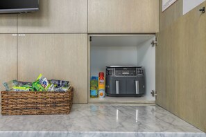 A kitchen with a microwave, a basket of groceries, and a coffee maker. - Luxury High Rise Walkable Free Parking + Views (Kansas City)