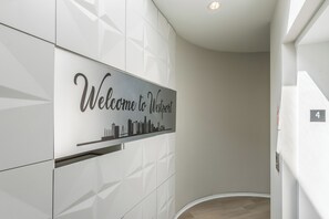A modern interior with a 'Welcome to Westport' sign, a geometric wall design, and a light-colored floor. - Luxury High Rise Walkable Free Parking + Views (Kansas City)