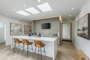 A modern kitchen with a central island, bar stools, recessed ceiling lights, and artwork on the walls. - Luxury High Rise Walkable Free Parking + Views (Kansas City)