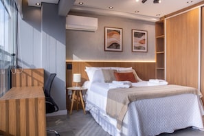 Ein modernes Hotelzimmer mit Bett, Nachttisch, Lampe, Klimaanlage, Kunstwerken und Holzvertäfelung.