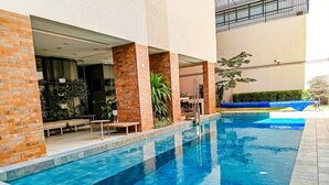 Ein Schwimmbecken mit klarem, blauem Wasser, umgeben von einer Ziegelmauer und einer Glaseinfriedung.