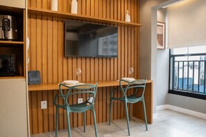 Eine moderne Küche mit integriertem Fernseher, Holzvertäfelung, zwei turquoisefarbenen Stühlen und einem Fenster mit Blick auf die Stadt.
