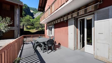 A balcony with a table and chairs, a wooden fence, and a mountain view.