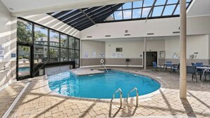 Una piscina interior con paredes de vidrio transparente, suelo de baldosas y techo cubierto.