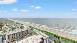 Un hotel frente al mar con varias edificaciones, una playa y una piscina.