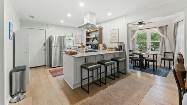 Een moderne keuken met een centraal eiland, barkrukken en een eethoek met uitzicht op de omgeving.