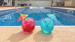 Twee drankjes met parasols bij een zwembad.