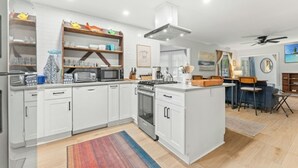 Een moderne keuken met witte kasten, een centraal eiland en een eetgedeelte met een bar.