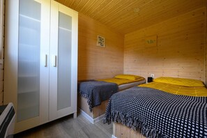 Une chambre dans un chalet en bois, avec deux lits, une armoire et un panneau accroché au mur.