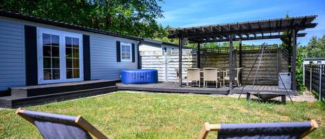 A small house with a patio, two chairs, a table, and a covered area.