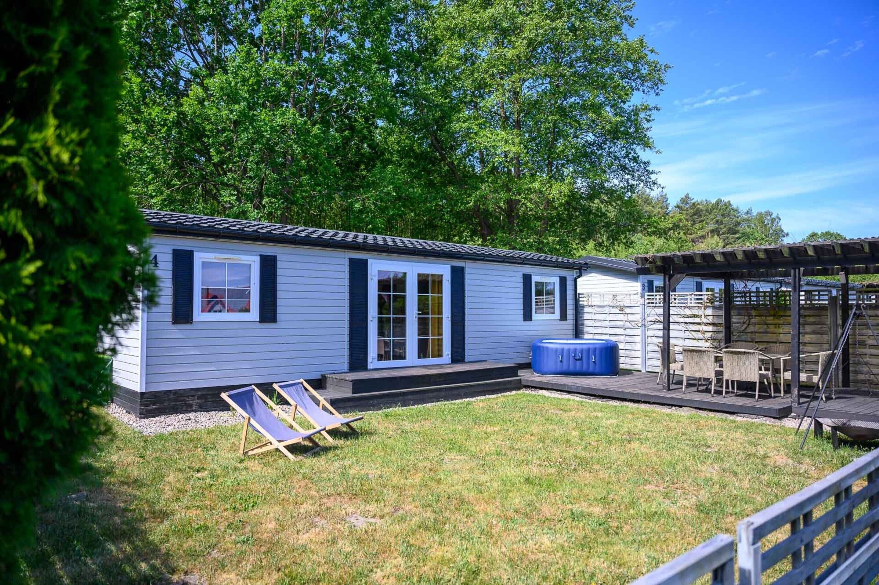 A single-story house with a covered patio, a hot tub, and a lawn.
