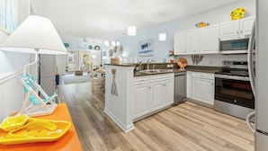 Une cuisine moderne avec des meubles blancs, un îlot central et un réfrigérateur en acier inoxydable.