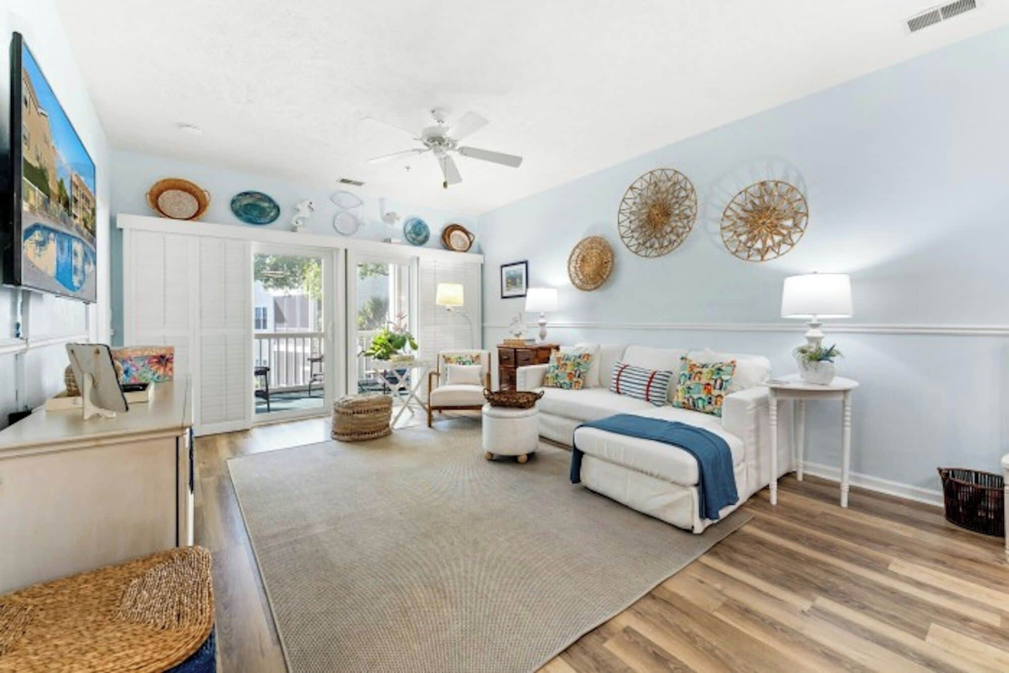 A living room with a white sofa, a coffee table, a TV, and a ceiling fan.