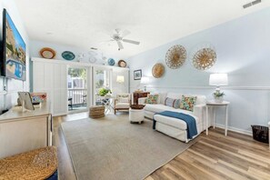 Ein Wohnzimmer mit einem weißen Sofa, einem Couchtisch, einem Fernseher und einem Deckenventilator.