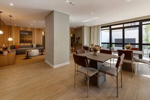 Ein modernes Interieur mit Essbereich, einer Sofagarnitur und einem großen Fenster, das für natürliches Licht sorgt.