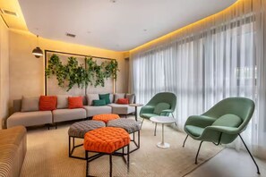 A modern living room with a sofa, ottomans, chairs, a small table, and a decorative wall with plants. - Studio Clean - Pinheiros (São Paulo)
