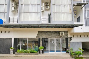 A modern building with a glass entrance, air conditioning units, and potted plants. - Hotel O near Taman Wisata Alam Punti Kay (Palembang)
