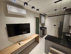 Eine moderne Küche mit Flachbildfernseher, Backofen und einer Sitzbank.