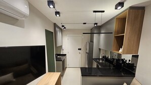 Une cuisine moderne dotée d’un îlot central, d’appareils électroménagers intégrés et d’un coin salon avec un canapé et une table.
