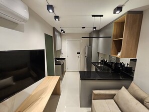 Eine moderne Küche mit einer zentralen Kochinsel, integrierten Geräten und einer Sitzecke mit Sofa und Tisch.