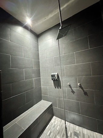 A modern shower with a rain showerhead, a bench, and a wall-mounted control panel.. Casa Completa: Confort, Alberca y Asador.