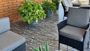 A covered patio area with brick walls, outdoor furniture, and potted plants. - Casa Completa: Confort, Alberca y Asador. (Fraccionamiento El Chaparral)