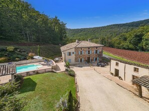 Ein Gebäude aus Stein mit einem Pool, umgeben von einem gepflegten Rasen und Bäumen.