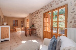 Ein Zimmer mit Steinwand, Holztür, weißem Sofa und einem Essbereich mit Stühlen und Tisch.