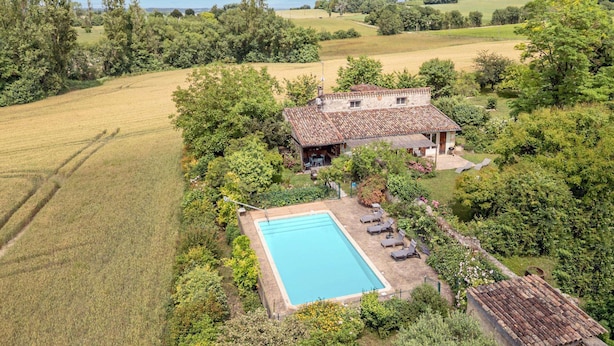 Ein Anwesen auf dem Land mit Pool, einem Steinhaus und umliegenden Feldern.