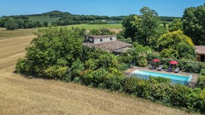 Ein ländliches Anwesen mit Swimmingpool, einem Steinhaus und umgebender Vegetation.