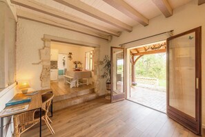 A rustic interior with a wooden dining table, wicker chairs, a staircase leading to a patio, and a view of greenery outside. - Le Brame - Three Bedroom Villa, Sleeps 6 (Dévillac)