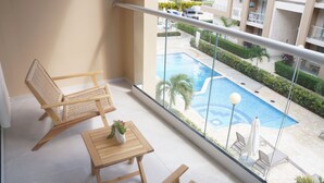 A balcony with a wooden chair, a small table, and a potted plant. - Modern 2 Bed 2 Bath apartment in Playa Nueva Romana - Beach, PGA Golf and Pools (La Caña)