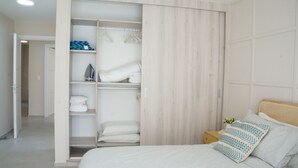 A bedroom with a bed, a wooden wardrobe, and a nightstand. - Modern 2 Bed 2 Bath apartment in Playa Nueva Romana - Beach, PGA Golf and Pools (La Caña)
