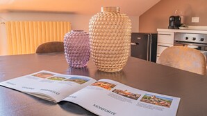 Et spisebord med et åbent magasin, to dekorative vaser og et køkken i baggrunden.