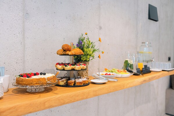 A buffet with various desserts and a vase of flowers.