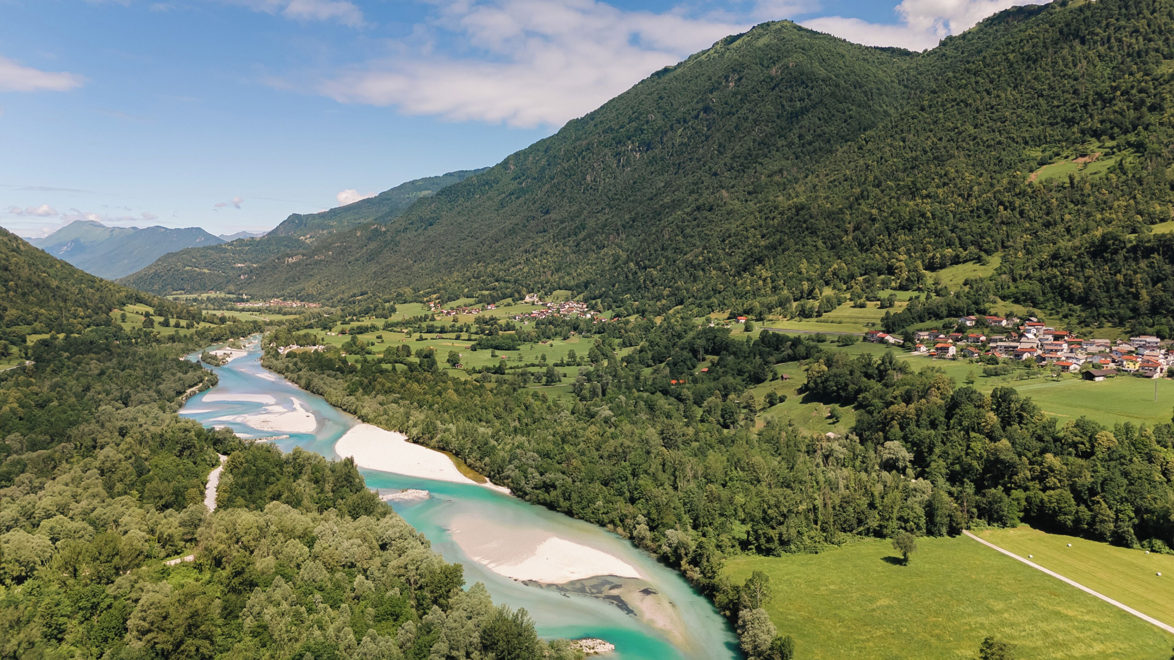 Un fiume serpeggia attraverso una valle, con una cittadina sulla destra.