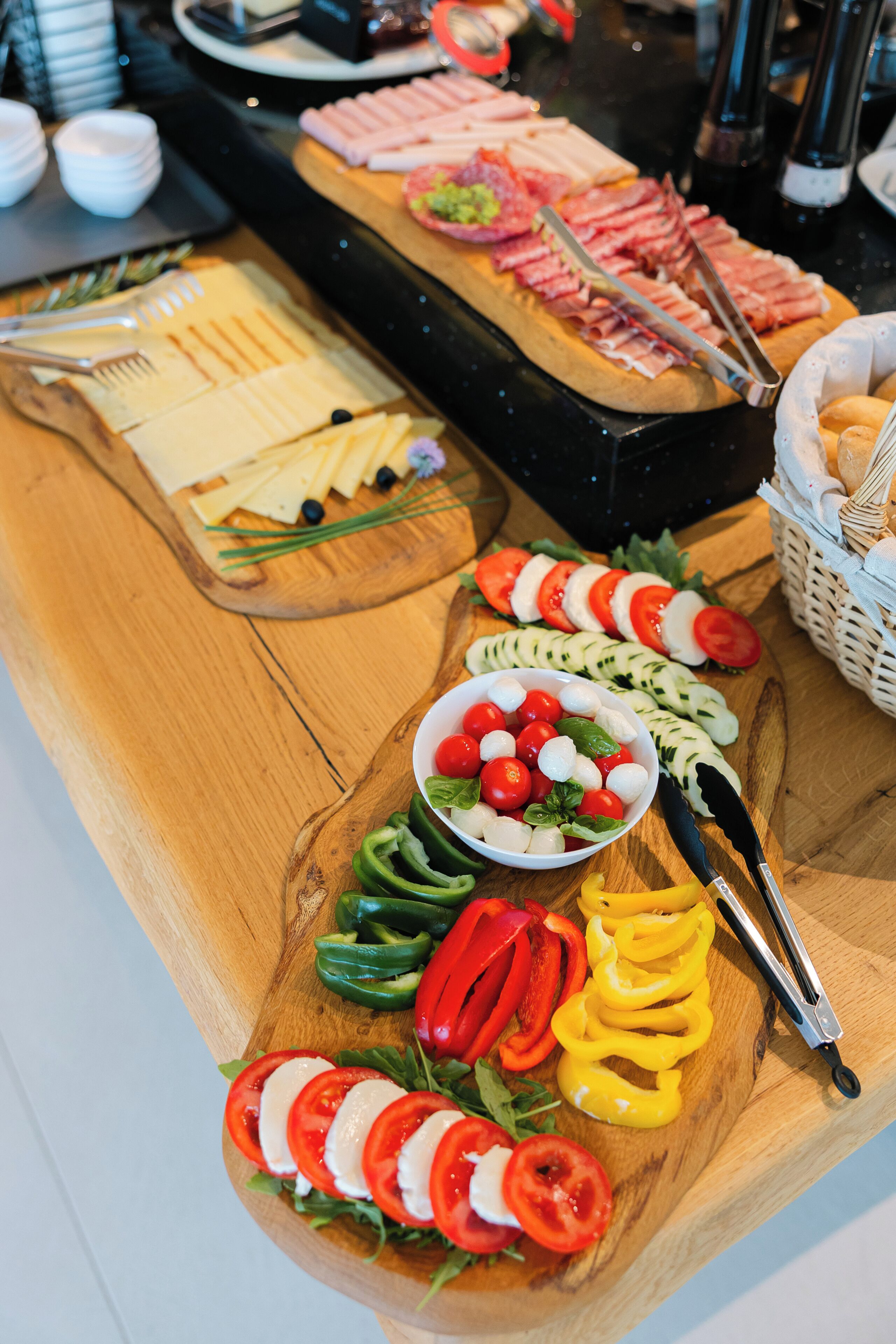 A buffet with various food items including sliced meats, cheeses, and fresh vegetables.