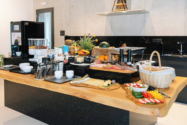 Un comptoir de buffet avec une machine à café, des fruits et divers aliments.