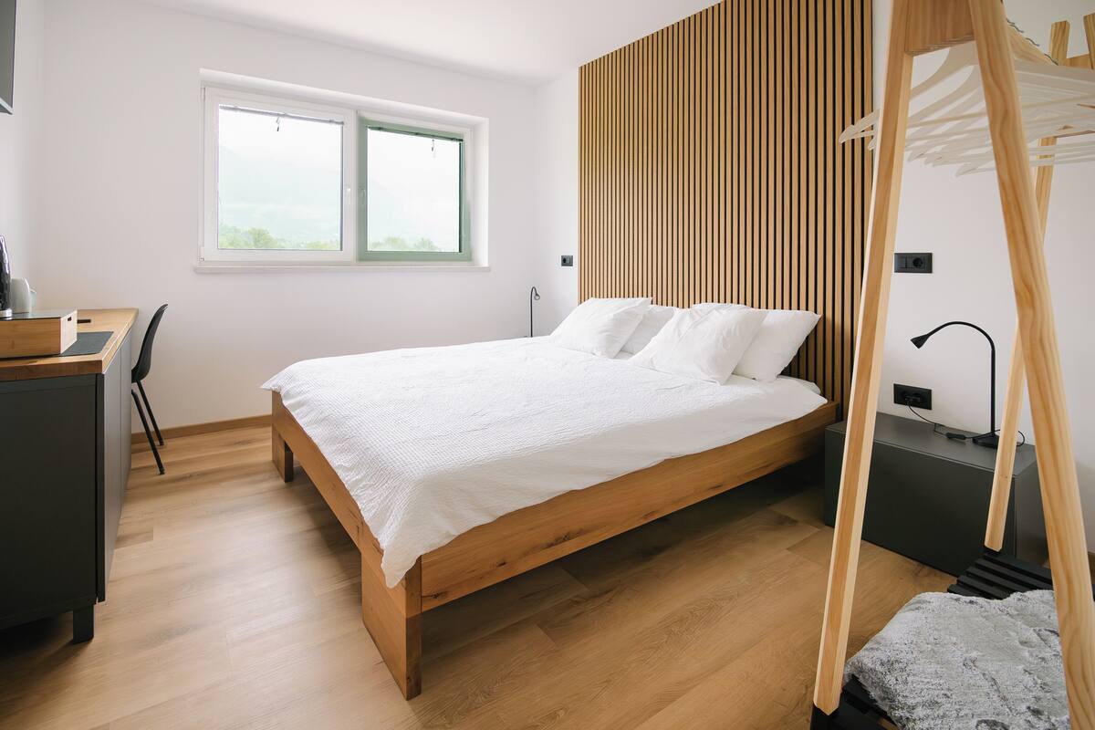 A bedroom with a wooden bed, a desk, and a window.