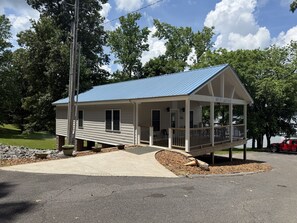 A small, single-story building with a blue roof, a porch, and a sign that reads 'BAY SIDE YACHT SALES.'