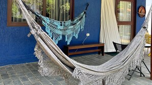 Una hamaca en una habitación con paredes azules, techo de madera y un banco.