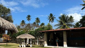 Una piscina con una estructura de techo de paja, un edificio de ladrillo y palmeras.